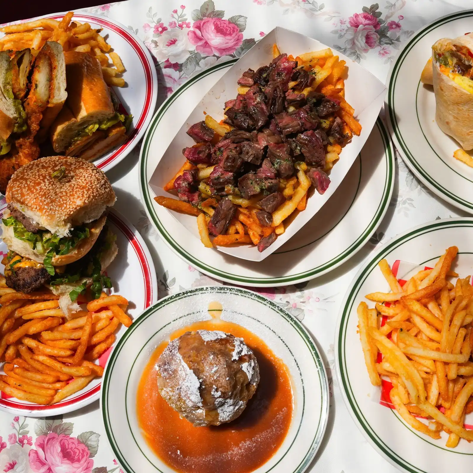 Overhead table spread at Uncle Rocco in Hoboken - burgers, sandwiches, a wrap, steak over fries and sides of fries